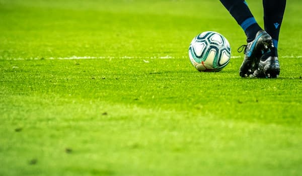 Ballon de football sur la pelouse au pied d’un joueur
